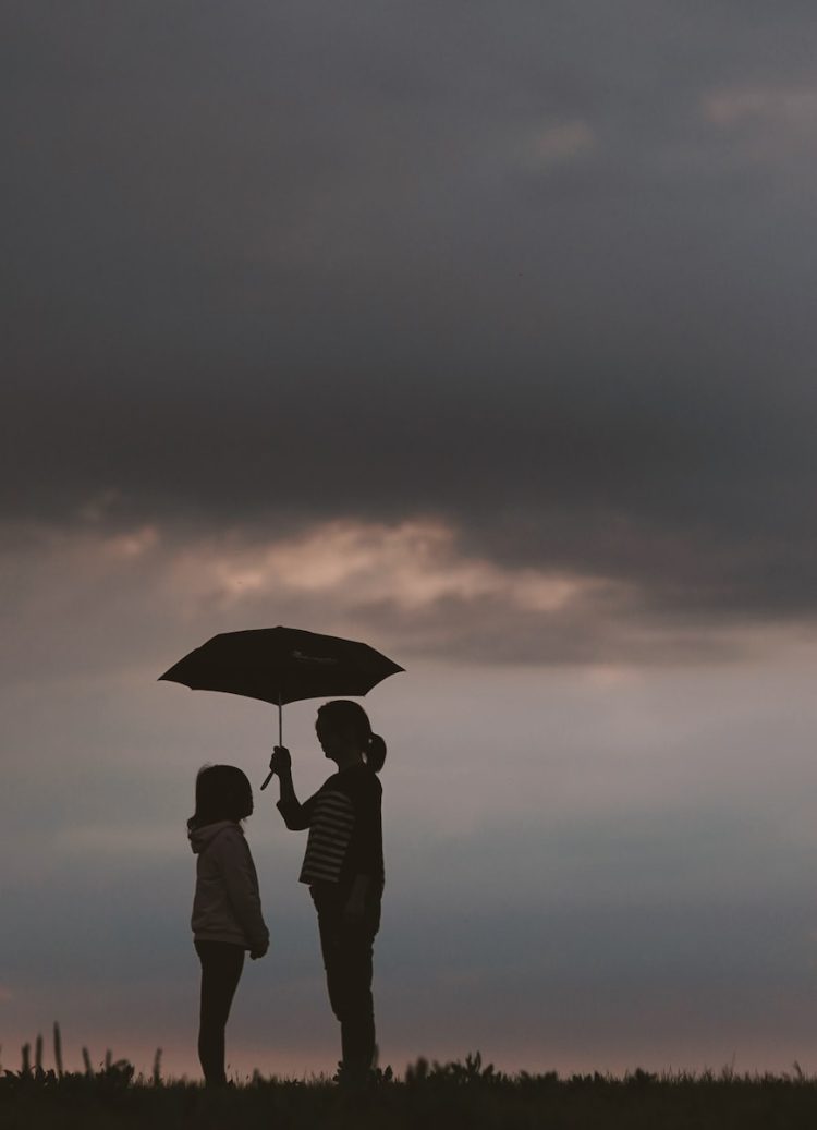 une mère tient le parapluie pour sa fille par temps orageux. Après un test ADN de maternité