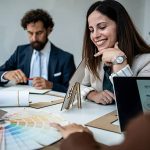 Architecture team collaborating on a new real estate project, reviewing a house model and color swatches during a business meeting in their modern office