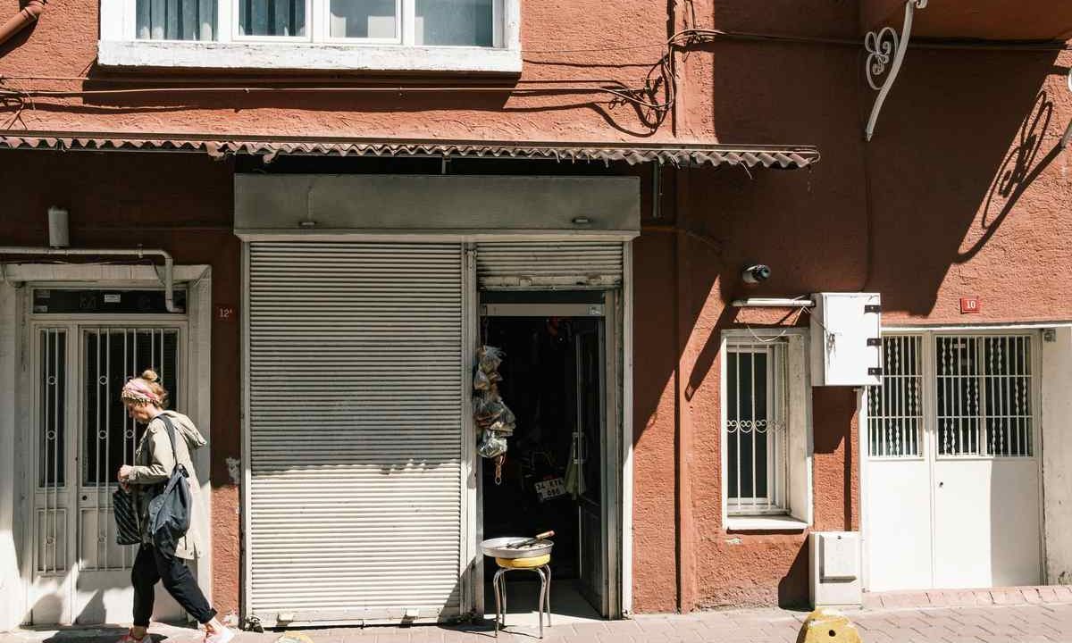 Une femme passe devant une boutique fermée dans un immeuble rouge
