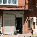 Une femme passe devant une boutique fermée dans un immeuble rouge