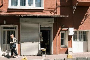 Une femme passe devant une boutique fermée dans un immeuble rouge