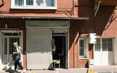 Une femme passe devant une boutique fermée dans un immeuble rouge