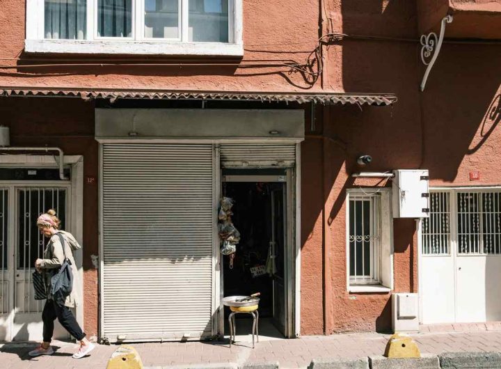 Une femme passe devant une boutique fermée dans un immeuble rouge