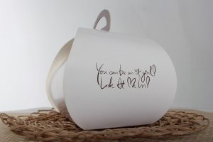 Objet blanc avec message écrit, sur un tapis, arrière-plan gris
