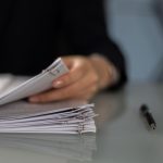 Main tenant classeur de documents sur table, stylo à côté