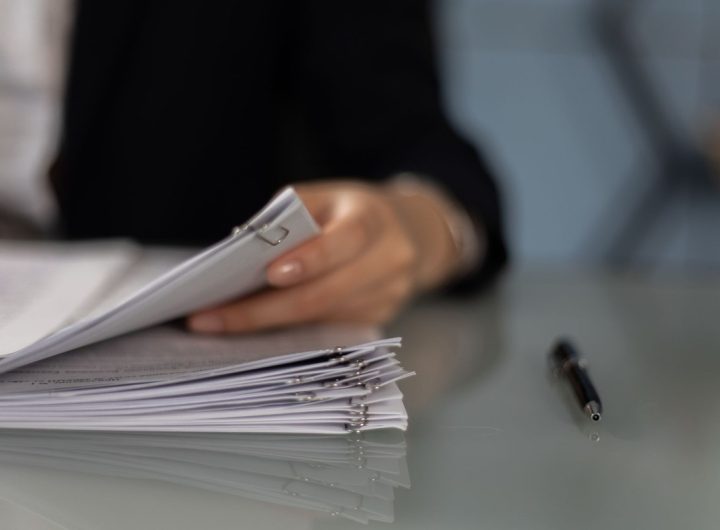 Main tenant classeur de documents sur table, stylo à côté