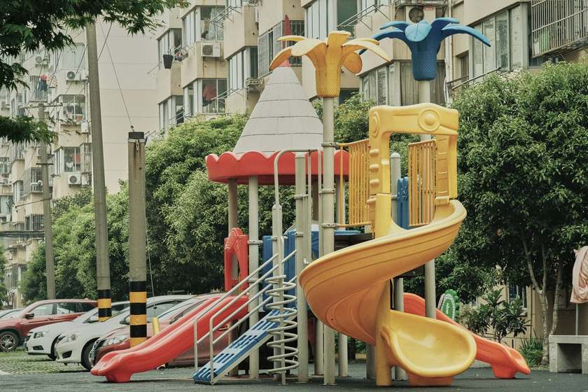 Structure de jeu colorée avec toboggans et balançoire, dans un parc urbain Structure de jeu colorée avec toboggans et balançoire, dans un parc urbain