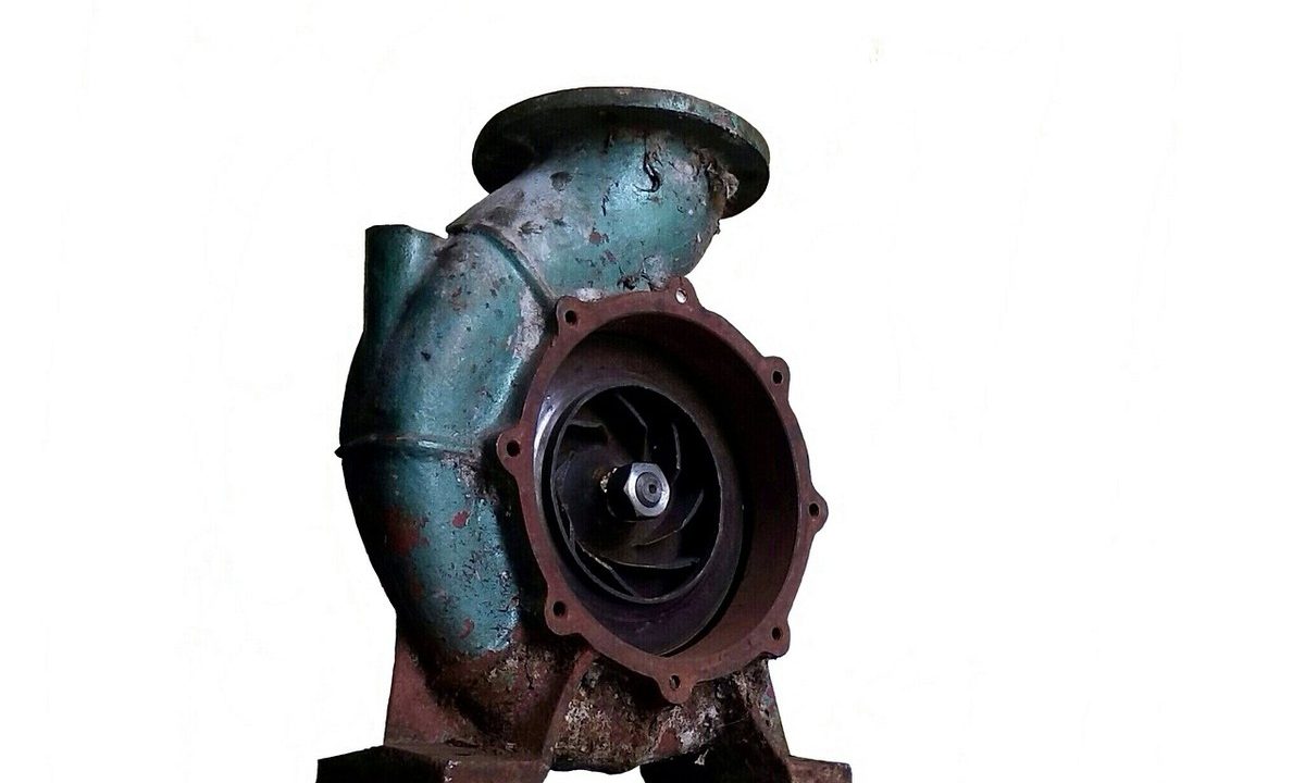Pompe industrielle rouillée avec turbine apparente, fixée sur socle
